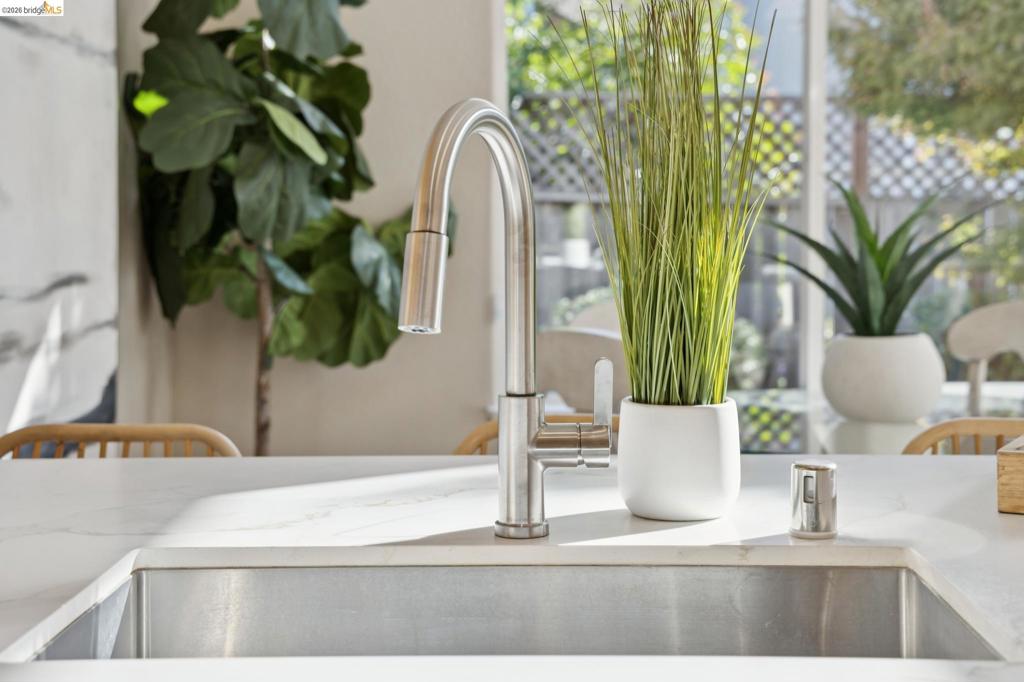 Undermount stainless steel sink featuring a high-arc brushed nickel pull-down faucet and a stone-surface countertop