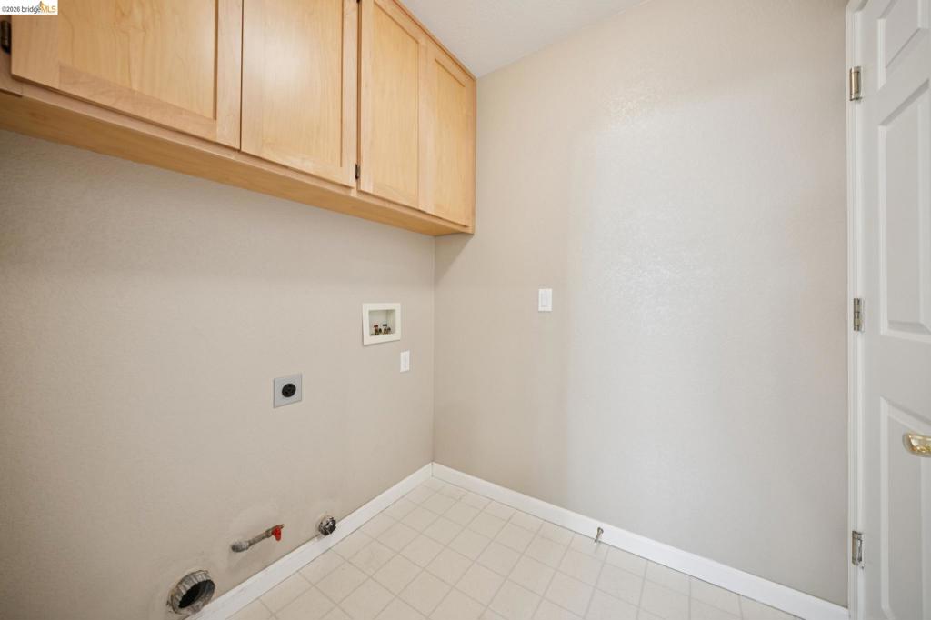 Utility area featuring light-finish wood cabinetry, tiled flooring, and designated washer and dryer hookups
