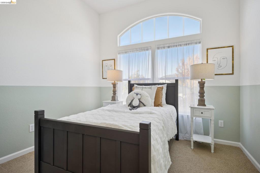 Vaulted ceiling featuring an arched window, neutral wall-to-wall carpeting, and two-toned wall paint