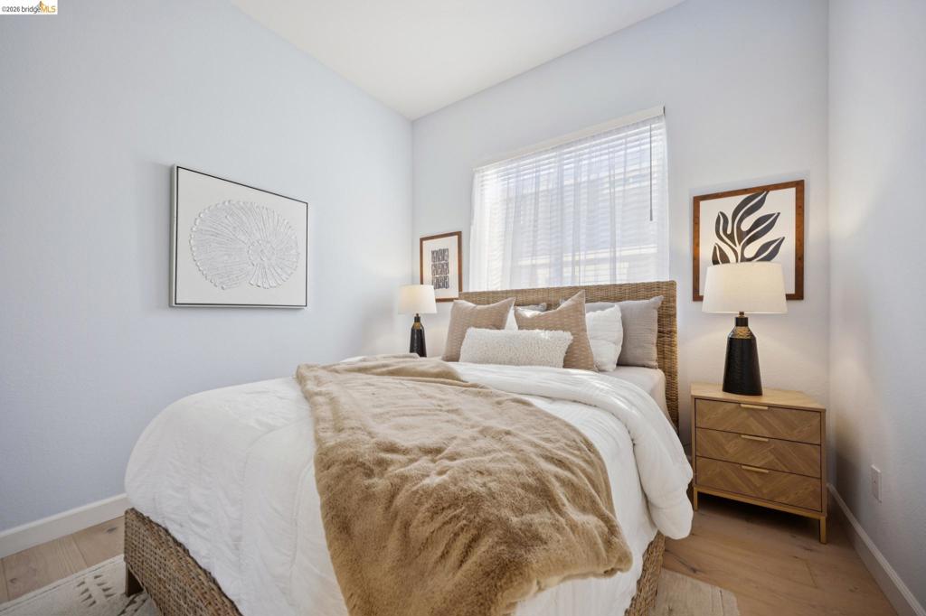 Light-filled room featuring wood-finish flooring and a window with horizontal blinds