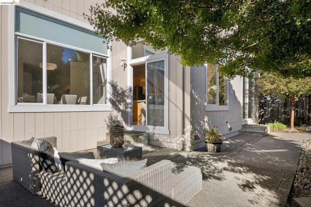 Exterior patio featuring a concrete surface, vertical wood siding, expansive multi-pane windows, and a sliding glass door