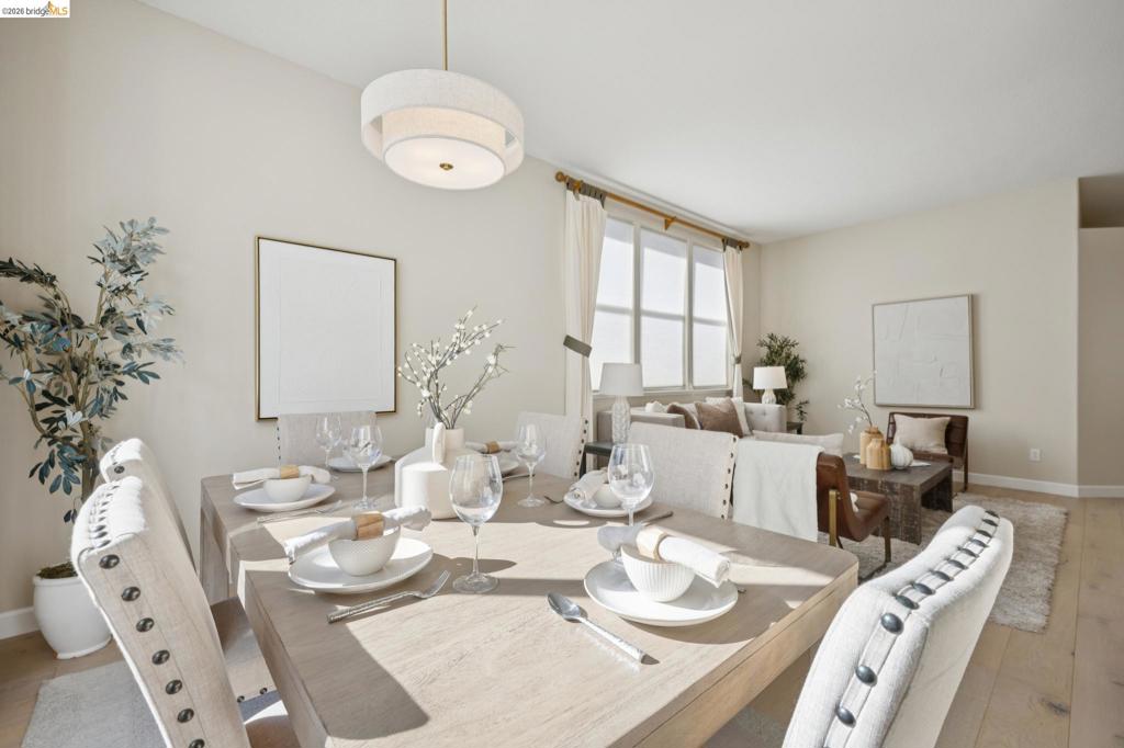 Open-concept area featuring light-toned wood-finish flooring, large multi-pane windows, and a modern drum-style pendant light fixture