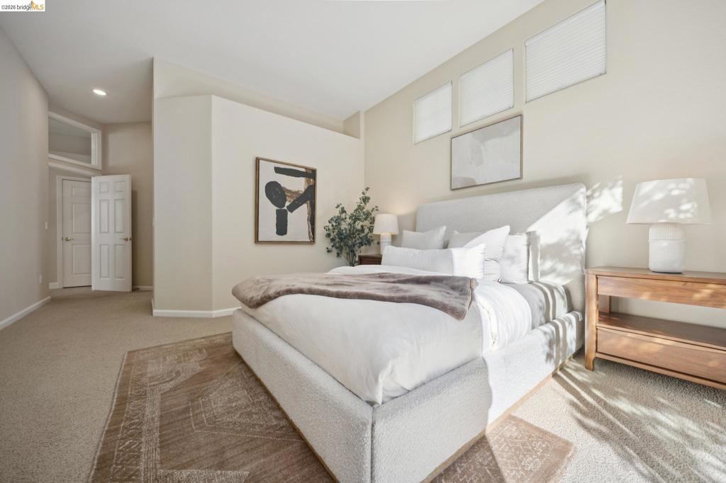 Neutral-toned interior space featuring carpeted flooring, high ceilings with recessed lighting, three upper-level transom windows, and a multi-panel interior door