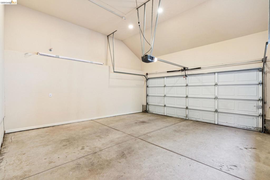Attached garage featuring high vaulted ceilings, concrete flooring, recessed lighting, and a multi-panel overhead door with an automatic opener