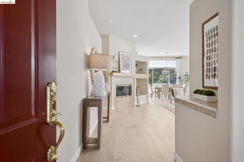 Entryway featuring wood-finish flooring, a fireplace with stone surround, a wood-finish mantel, and integrated shelving