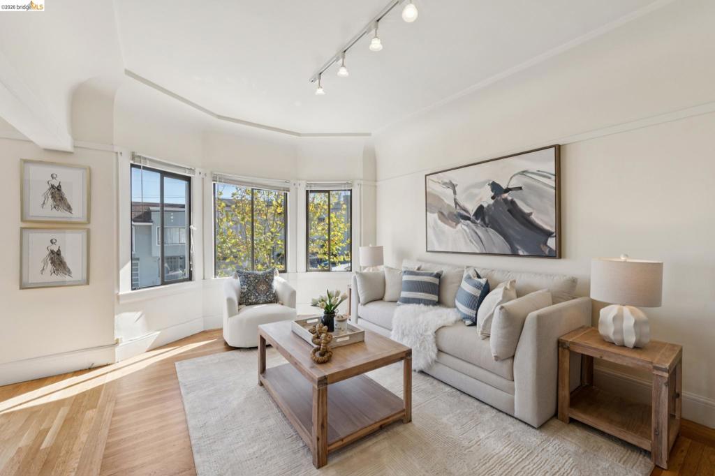Bay window featuring three paneled glass windows, wood-finish flooring, and adjustable ceiling-mounted track lighting