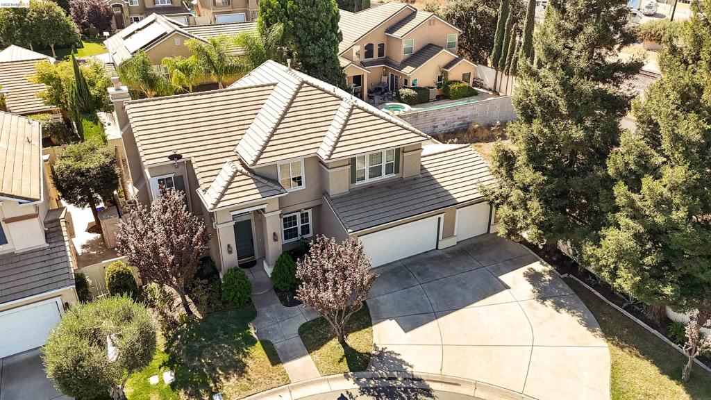 Two-story residence featuring a concrete tile roof, stucco exterior, three-car garage, and a spacious concrete driveway