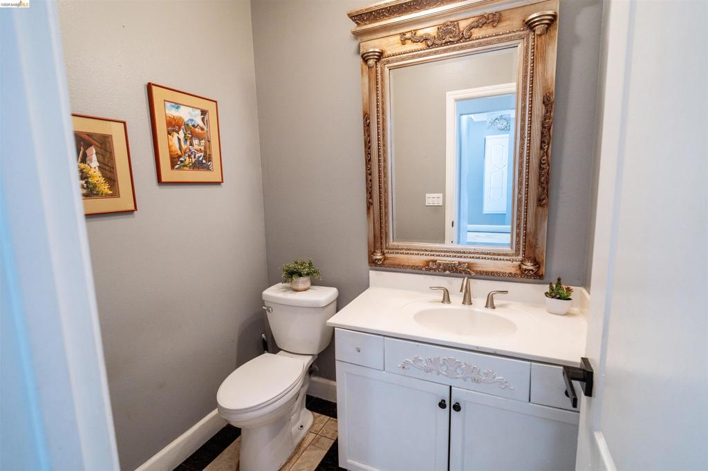 White vanity with a carved drawer panel, integrated basin, dual-handle brushed metal faucet, and an ornate, detailed frame mirror