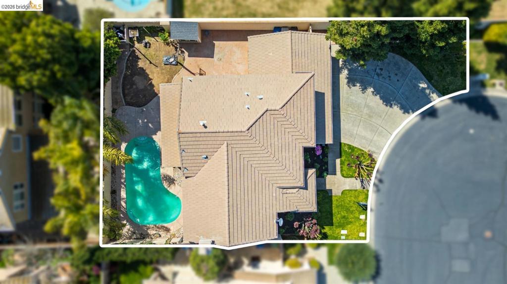Aerial perspective of the property featuring a concrete driveway, multi-gabled tile roof, swimming pool, and landscaped lawn areas