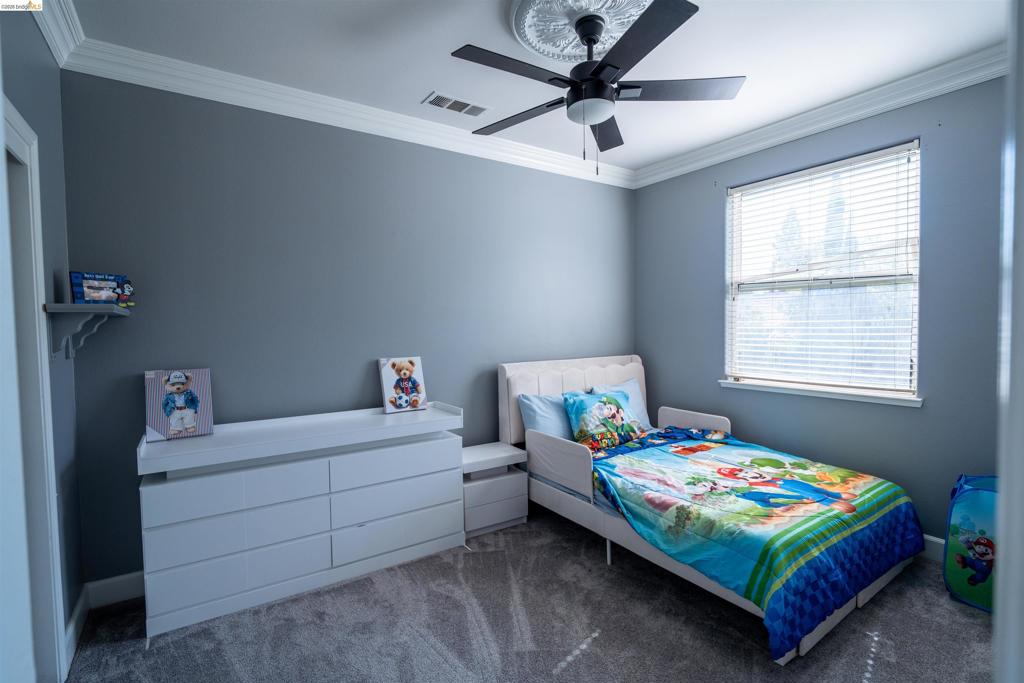 Room featuring neutral wall tones, crown molding, ceiling medallion, ceiling fan, and carpeted flooring