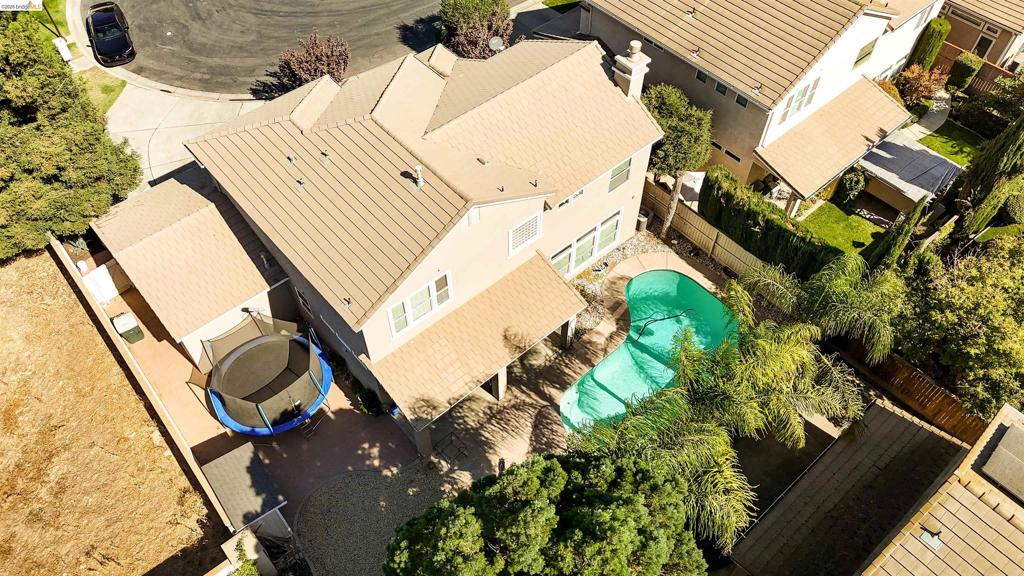 Two-story residence featuring a tile roof, an in-ground swimming pool, a covered patio, and mature landscaping