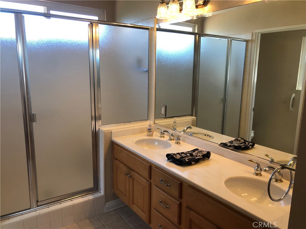 Primary bathroom with dual sinks and shower with seating