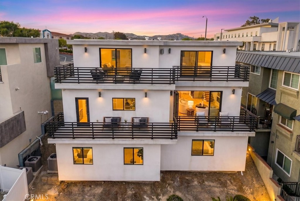 Rear of the home at dusk, with balconies on all three levels.