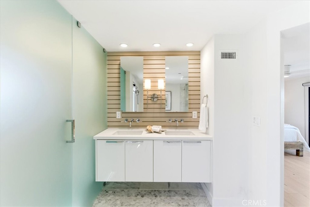 Bathroom with a floating vanity and frosted glass shower.