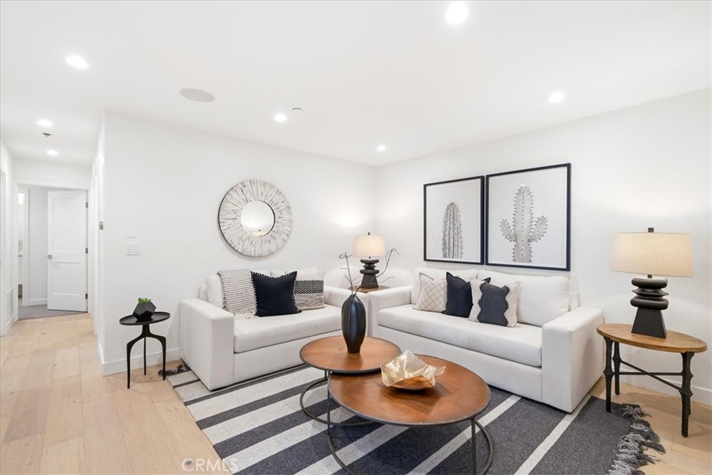 Living room with light hardwood floors and staged seating.