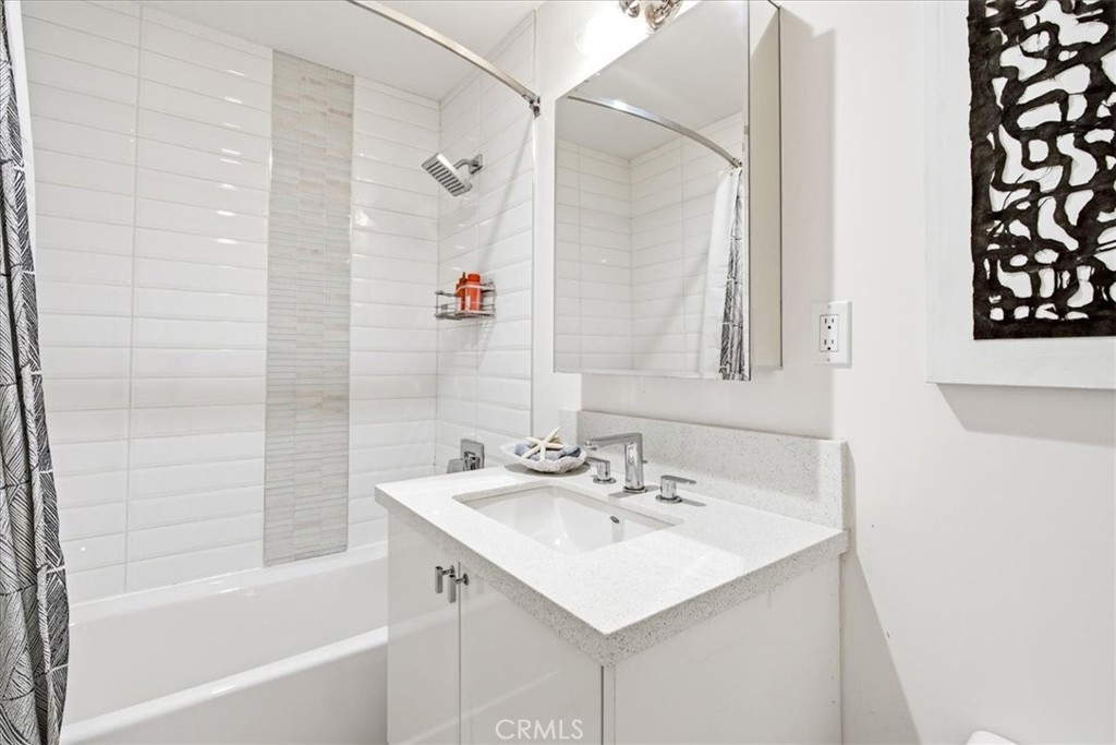 Bathroom with a tub and shower and a white vanity.