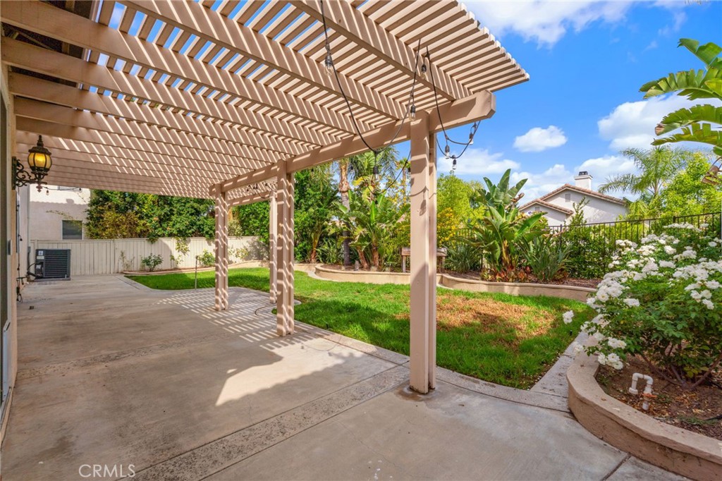 Inviting Backyard Patio Featuring A Spacious Pergola, Comfortable Outdoor Seating Areas, And Beautiful Tropical Landscaping, Perfect For Relaxing Or Entertaining.