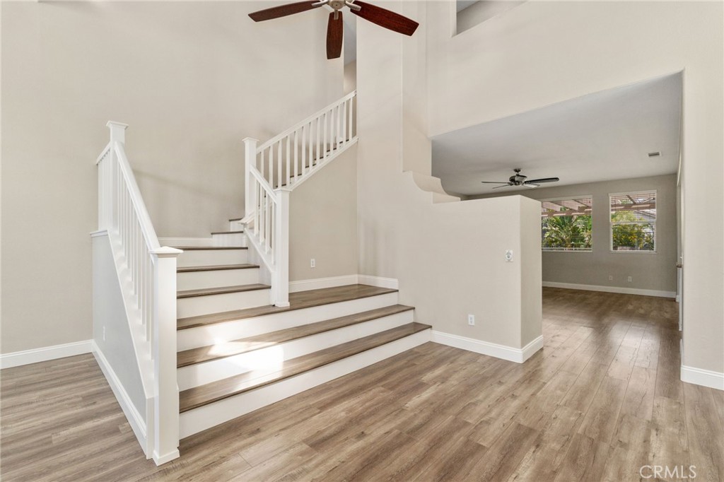 Beautiful Staircase Featuring White Railings, Wood-Look Flooring, And An Open View Toward The Spacious Family Room.