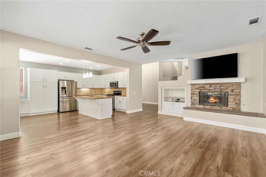 Beautiful Open-Concept Family Room Featuring A Stone-Surround Fireplace, Built-In Shelving, And A Seamless Connection To The Spacious Kitchen And Dining Area.