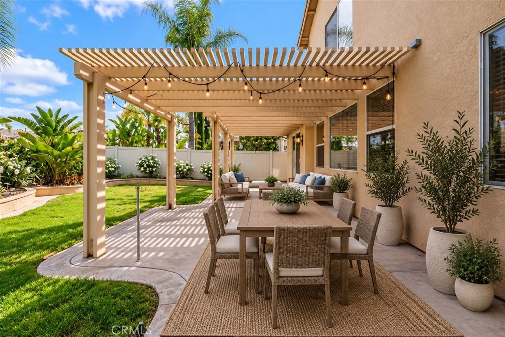 Spacious Pergola-Covered Patio Featuring An Inviting Outdoor Dining Area, Comfortable Seating, And Views Of The Beautifully Landscaped Backyard. Digitally Staged