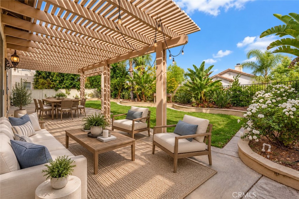 Inviting Backyard Patio Featuring A Spacious Pergola, Comfortable Outdoor Seating Areas, And Beautiful Tropical Landscaping, Perfect For Relaxing Or Entertaining. Digitally Staged