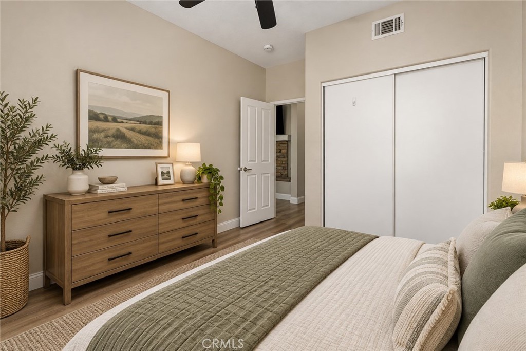 Another View Of The Bedroom Highlighting The Spacious Layout, Sliding-Door Closet, Ceiling Fan, And Attractive Wood-Look Flooring. Digitally Staged