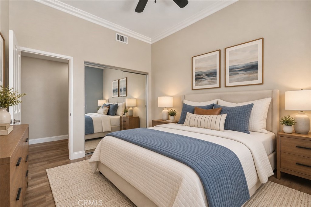 Another View Of The Secondary Bedroom Highlighting The Mirrored Closet Doors, Elegant Crown Molding, Generous Floor Space, And Attractive Wood-Look Flooring. Digitally Staged