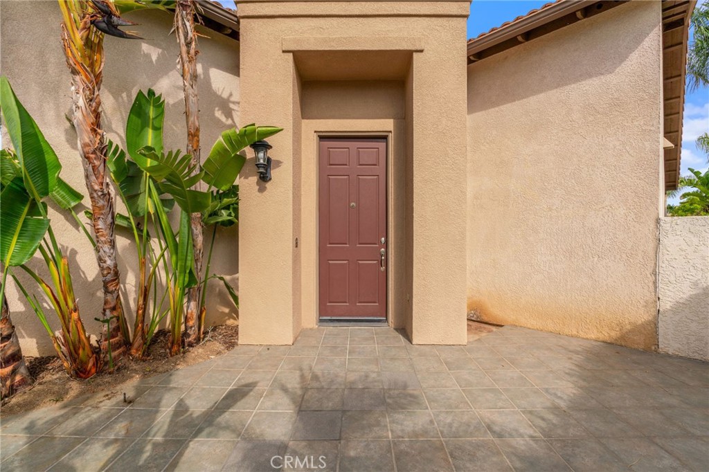 Welcoming Front Entry Featuring A Recessed Front Door, Spacious Paved Courtyard, And Beautiful Tropical Landscaping.