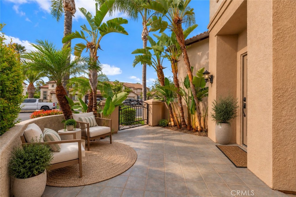 Inviting Front Courtyard Featuring A Spacious Paved Patio, Tropical Landscaping, And A Peaceful Setting For Outdoor Relaxation. Digitally Staged
