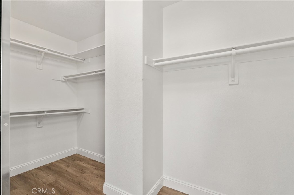 Generous Walk-In Closet Featuring Built-In Shelving, Multiple Hanging Areas, And Plenty Of Space For Clothing, Shoes, And Accessories.