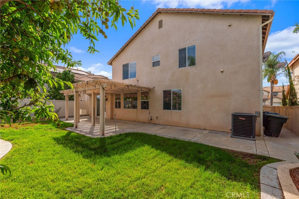 Another View Of The Backyard Highlighting The Two-Story Home, Generous Lawn Area, Pergola-Covered Patio, And Established Landscaping.
