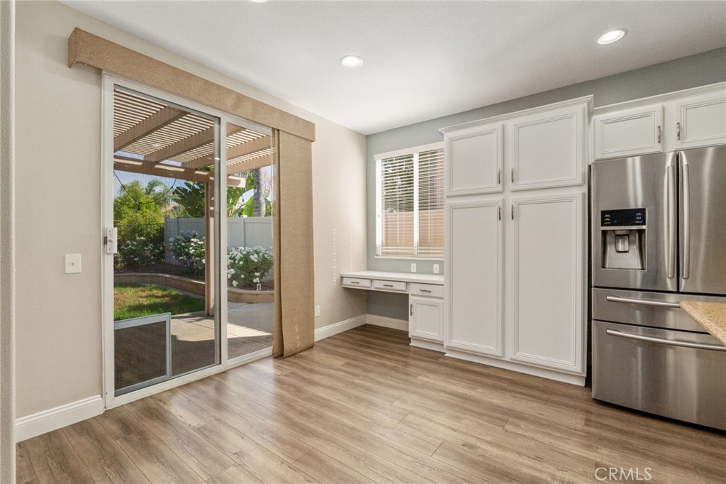 Charming Dining Area Featuring Wood-Look Flooring, Abundant Natural Light, Sliding Glass Door Access To The Backyard, And A Convenient Built-In Desk Area.