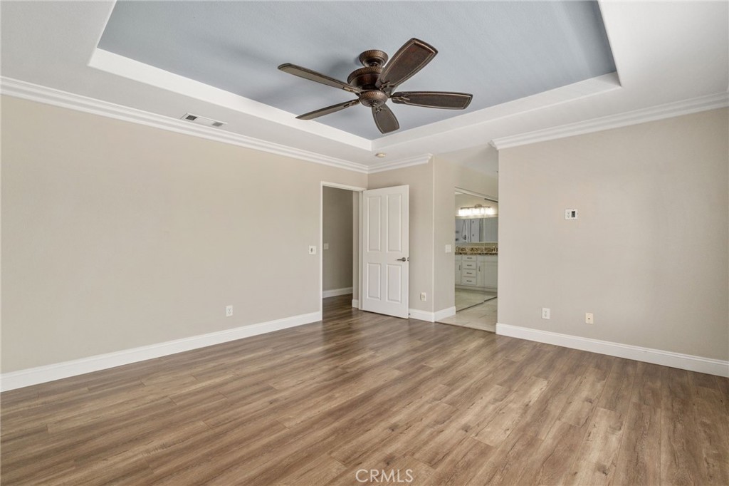 Another View Of The Spacious Primary Suite Highlighting The Elegant Tray Ceiling, Generous Floor Space, And Convenient Access To The Private Primary Bathroom.