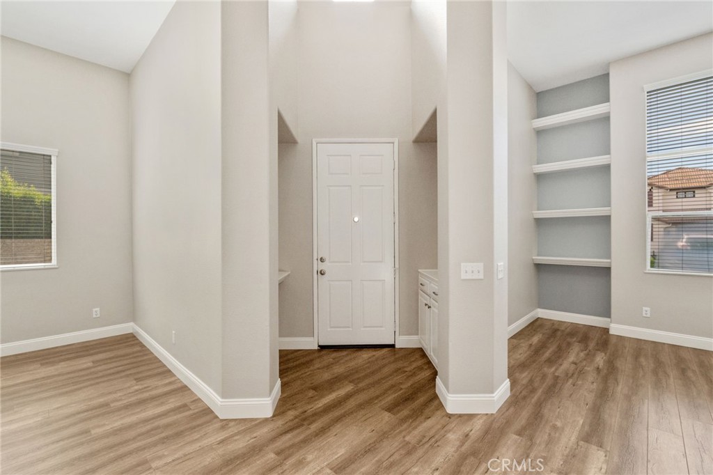Bright And Inviting Entryway Featuring Soaring Ceilings, Attractive Wood-Look Flooring, And An Open View Of The Versatile Front Living Spaces.