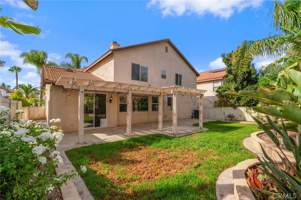Beautiful Backyard Featuring A Spacious Lawn, Expansive Pergola-Covered Patio, Mature Tropical Landscaping, And Plenty Of Room For Outdoor Enjoyment.