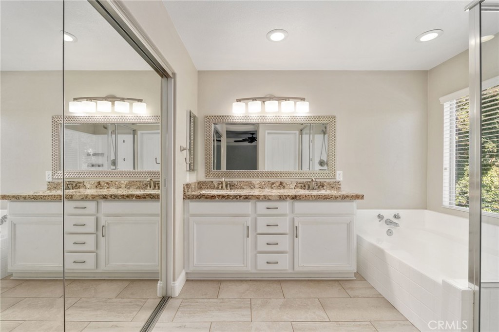 Spacious Primary Bathroom Featuring An Expansive Vanity With Generous Counter Space, Framed Mirror, Relaxing Soaking Tub, And Separate Glass-Enclosed Shower.