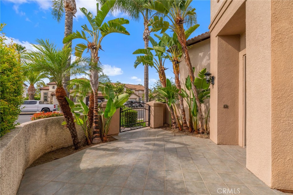 Inviting Front Courtyard Featuring A Spacious Paved Patio, Tropical Landscaping, And A Peaceful Setting For Outdoor Relaxation.