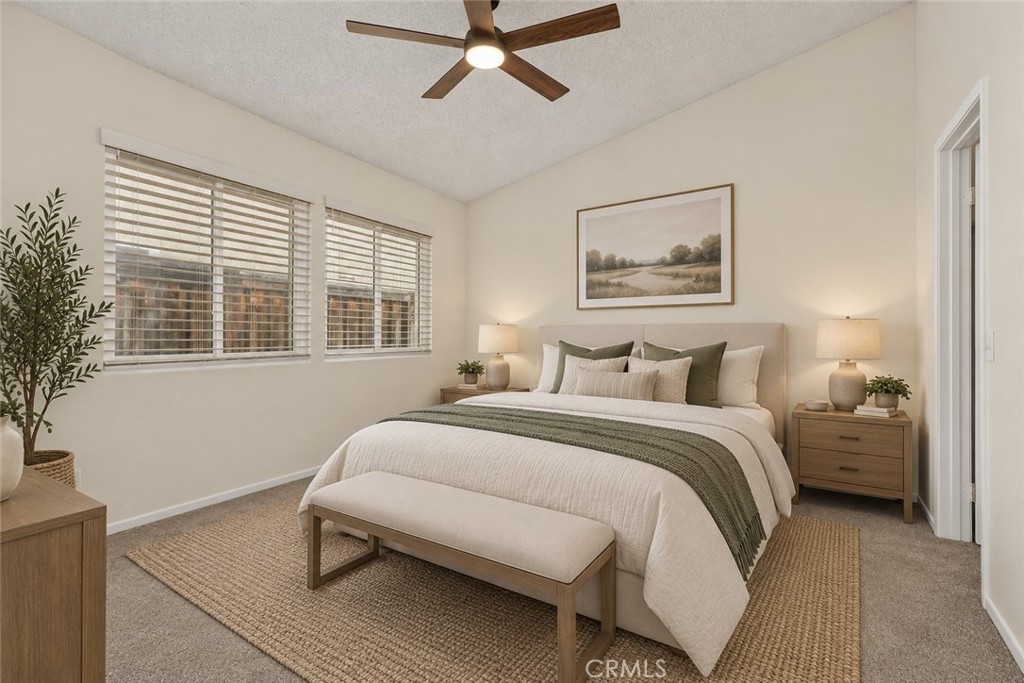 The comfortable primary bedroom features soft carpeting, a ceiling fan, and two windows providing natural light. Digitally Staged