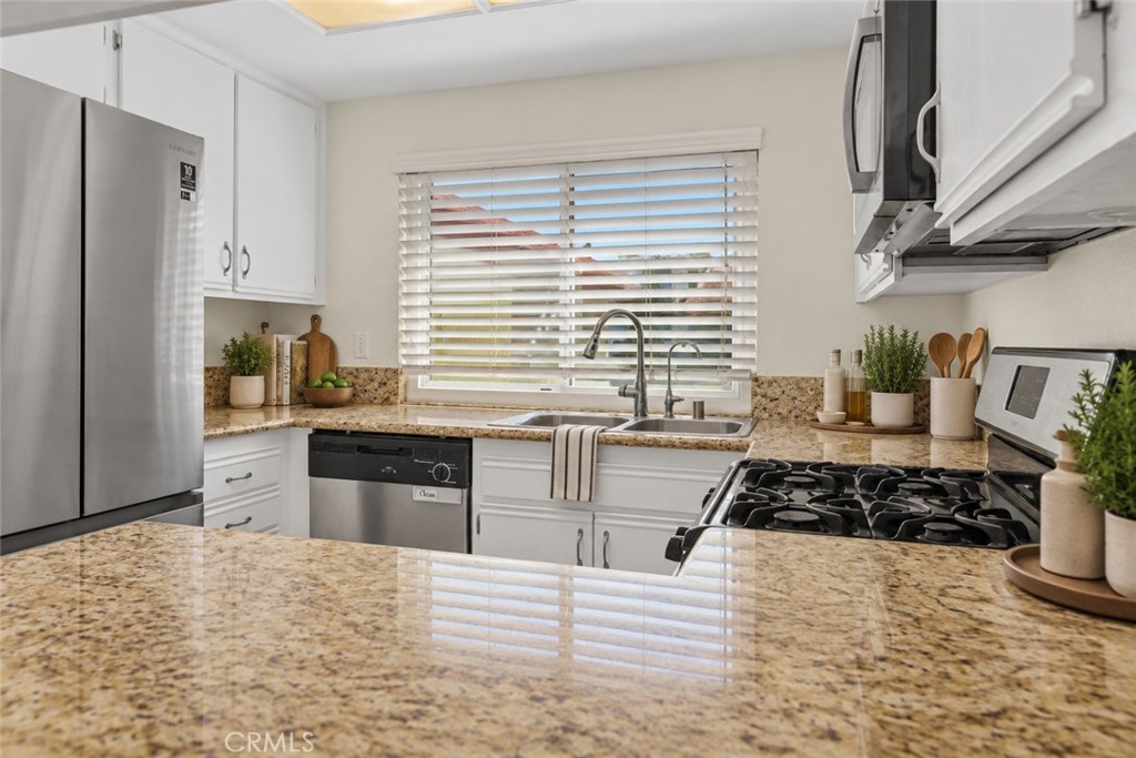 Another kitchen view highlights the granite countertops, double-basin sink beneath the window, and convenient countertop workspace. Digitally Staged