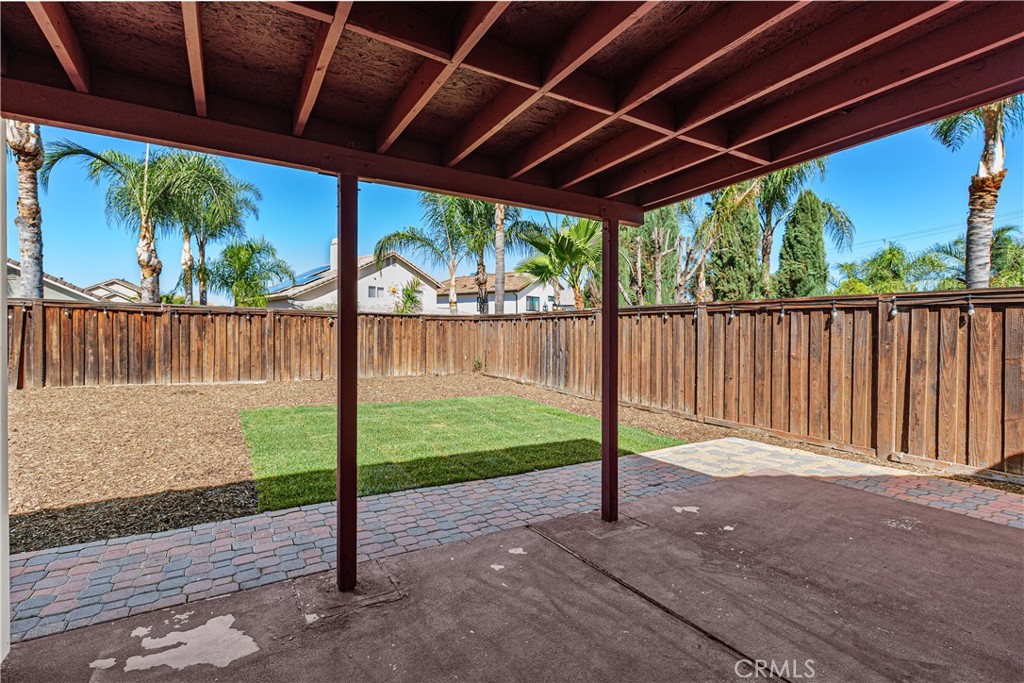 Covered backyard patio offering a shaded outdoor space to relax, entertain, or enjoy the surrounding yard.
