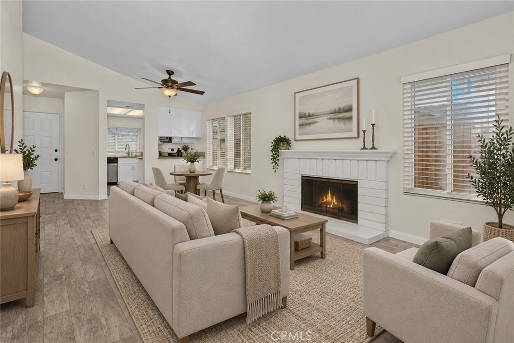 Another inviting view of the living room showcases the fireplace, natural light, and easy connection to the dining area and kitchen. Digitally Staged