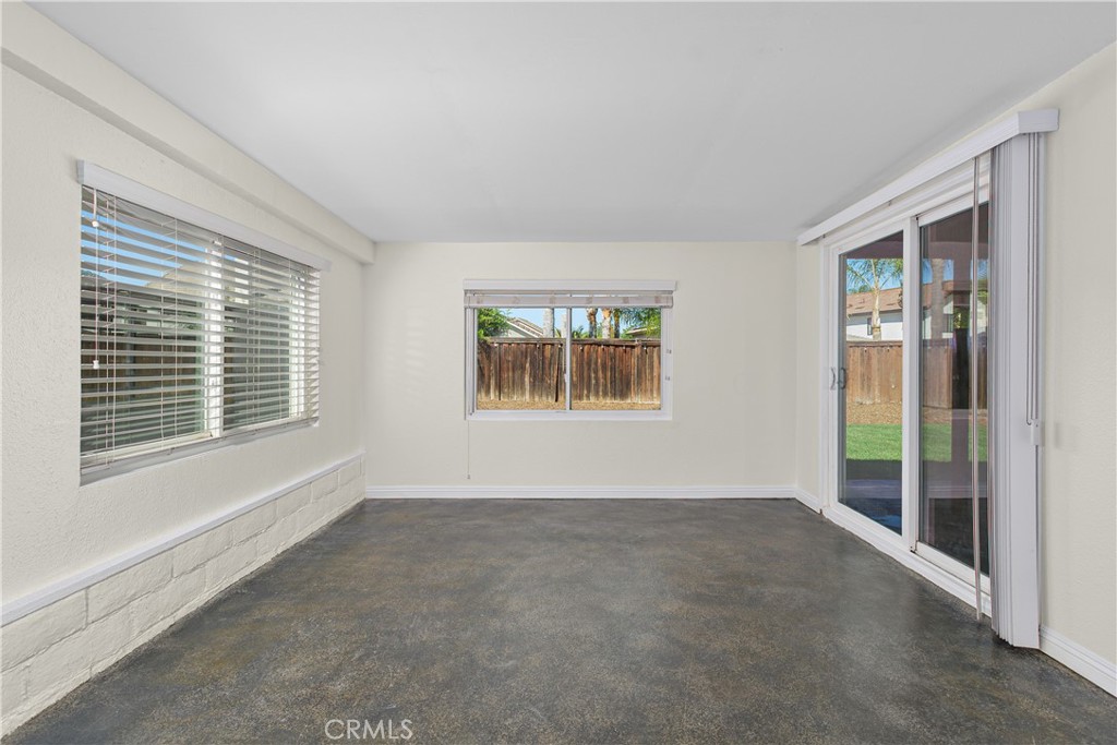 Versatile enclosed patio offering an inviting additional space to relax, with multiple windows and sliding glass doors overlooking the backyard.