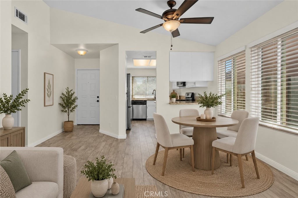 Dining area conveniently situated beside the kitchen, featuring a ceiling fan, large windows, and an open connection to the living space. Digitally Staged