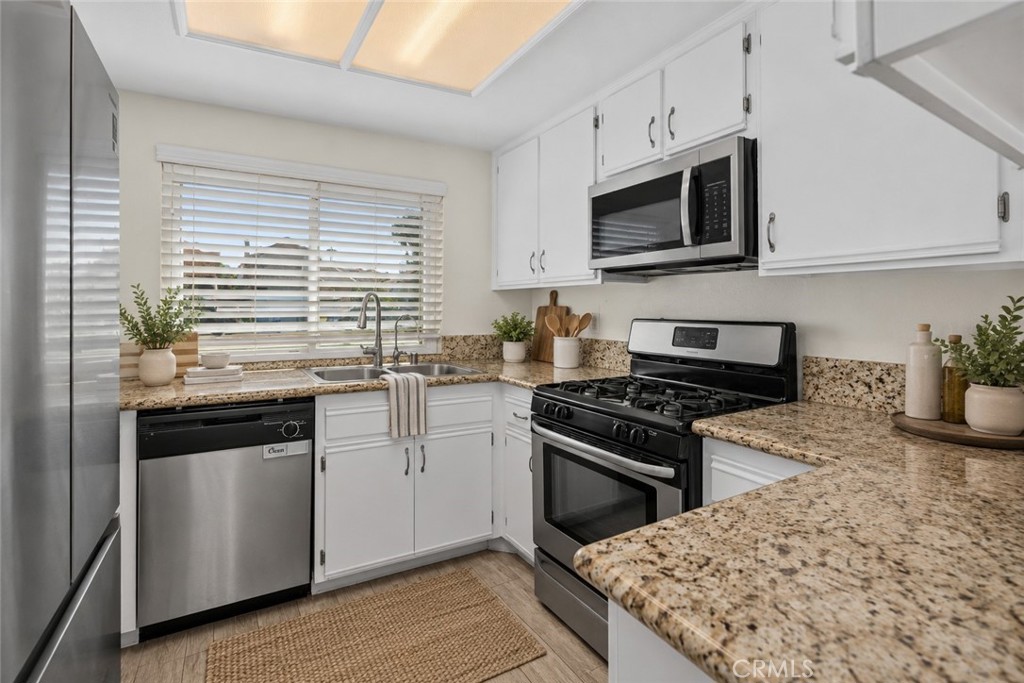 The kitchen features white cabinetry, granite countertops, stainless steel appliances, and a gas range for everyday cooking. Digitally Staged