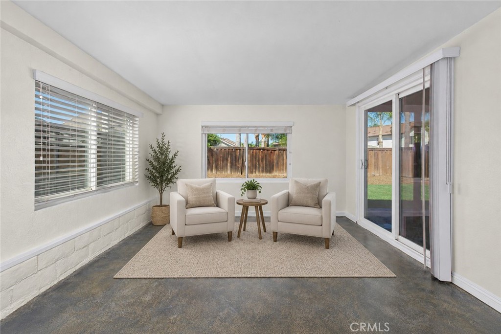 Versatile enclosed patio offering an inviting additional space to relax, with multiple windows and sliding glass doors overlooking the backyard. Digitally Staged Versatile enclosed patio offering an inviting additional space to relax, with multiple windows and sliding glass doors overlooking the backyard. Digitally Staged