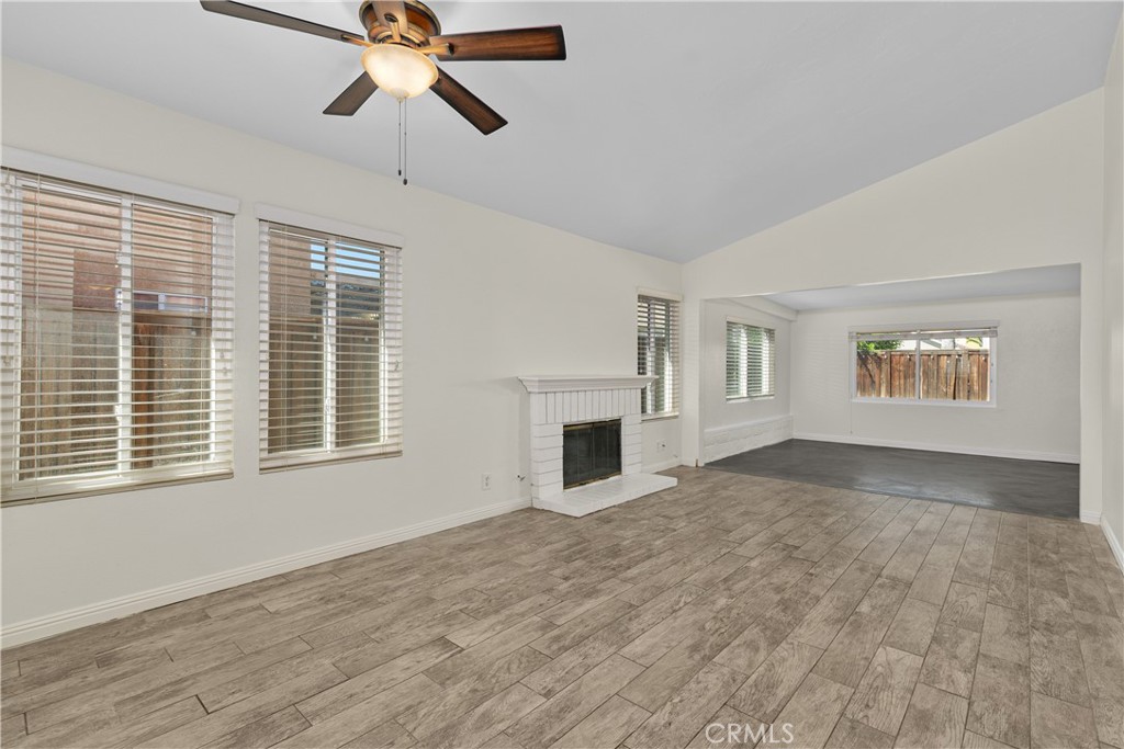 Bright and inviting living and dining areas featuring wood-look flooring, a cozy fireplace, and an open connection to the enclosed patio. Bright and inviting living and dining areas featuring wood-look flooring, a cozy fireplace, and an open connection to the enclosed patio.