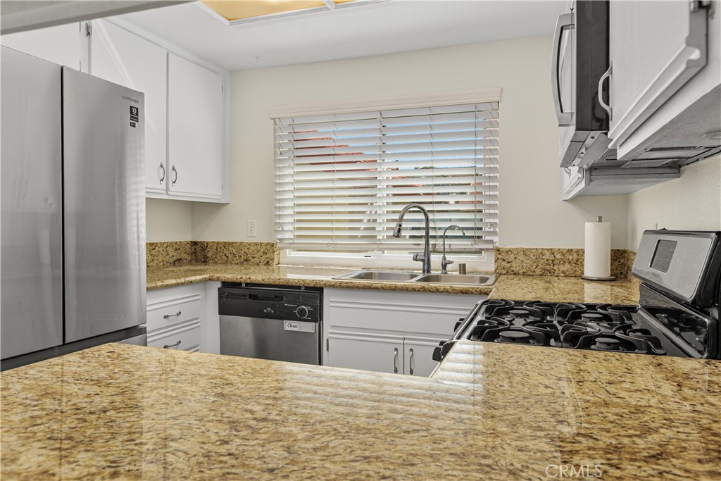 Another kitchen view highlights the granite countertops, double-basin sink beneath the window, and convenient countertop workspace.