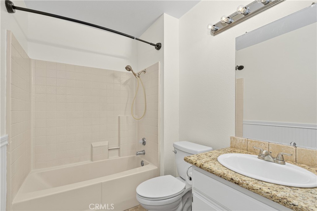 Additional full bathroom featuring a tub and shower combination, granite-topped vanity, and convenient storage.