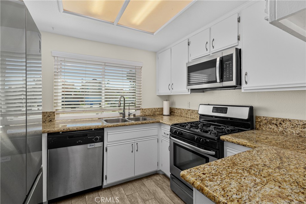 The kitchen features white cabinetry, granite countertops, stainless steel appliances, and a gas range for everyday cooking.