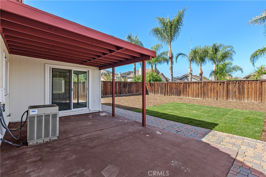 An additional view of the covered patio highlights the sliding glass doors, patio space, and convenient access to the backyard.